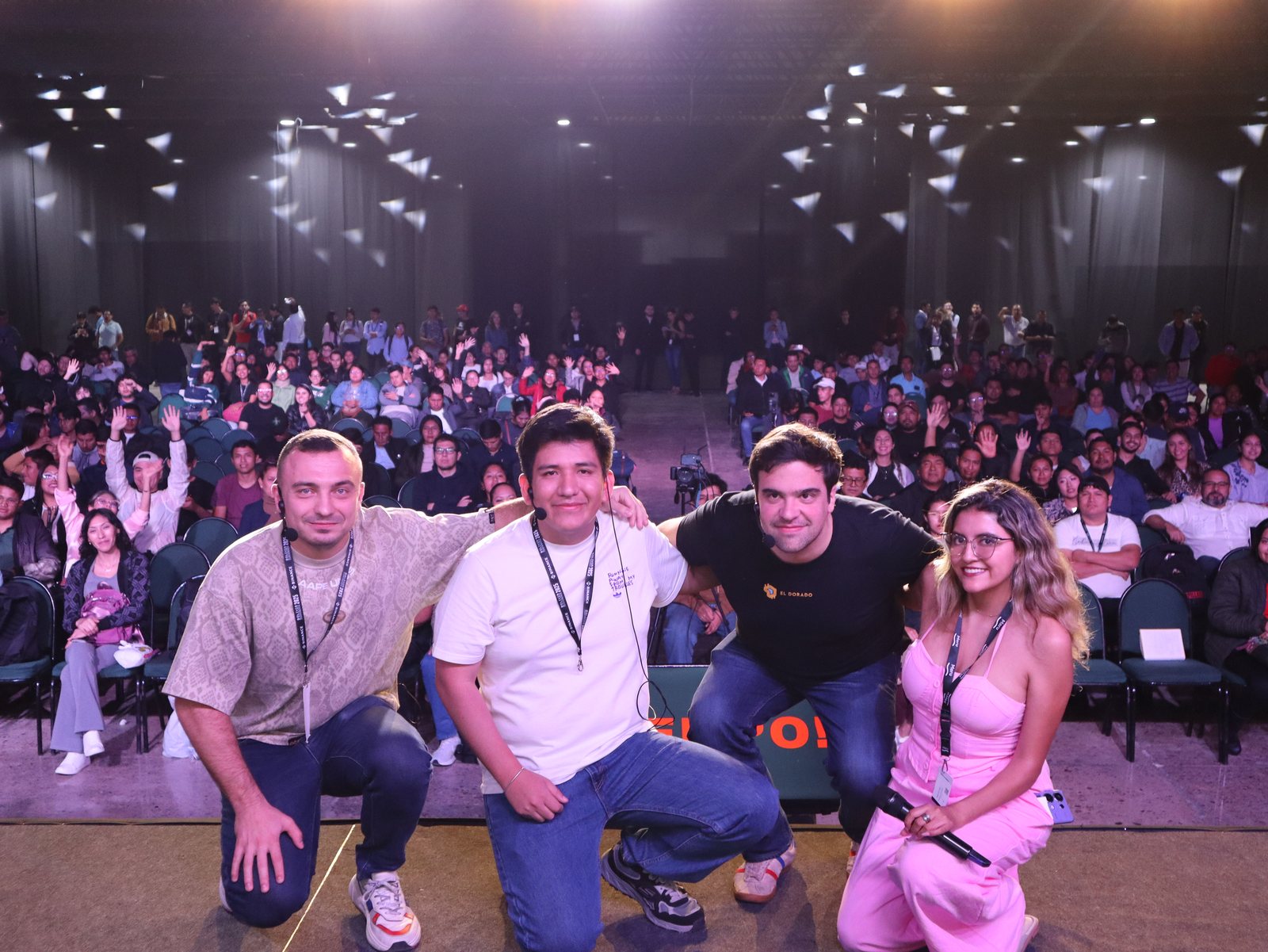 Foto grupal en el escenario con el auditorio lleno de fondo